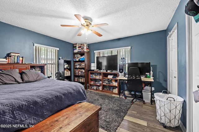 bedroom with a ceiling fan, a textured ceiling, and wood finished floors