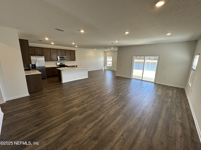 kitchen featuring stainless steel appliances, light countertops, visible vents, open floor plan, and dark brown cabinets