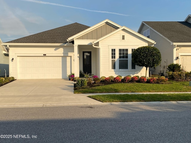 view of front of house featuring a shingled roof, concrete driveway, an attached garage, a front lawn, and board and batten siding