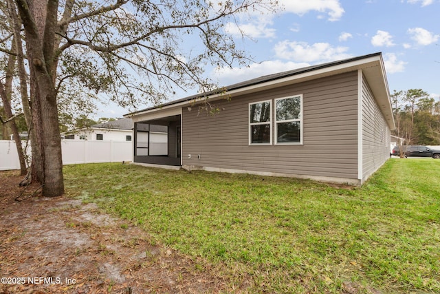 rear view of house with fence and a lawn