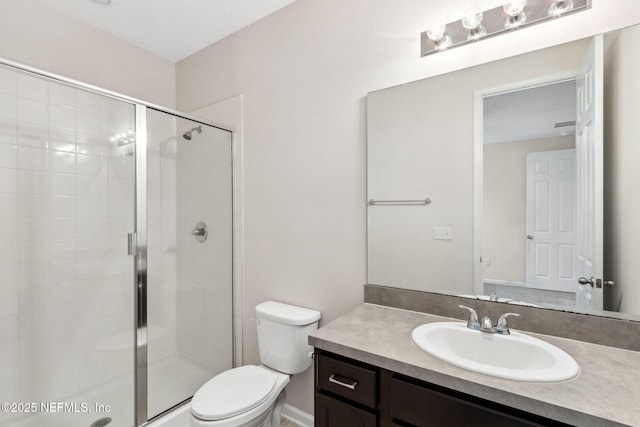 bathroom featuring toilet, a shower stall, and vanity