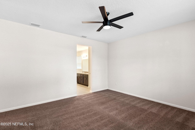 spare room with carpet floors, visible vents, and baseboards