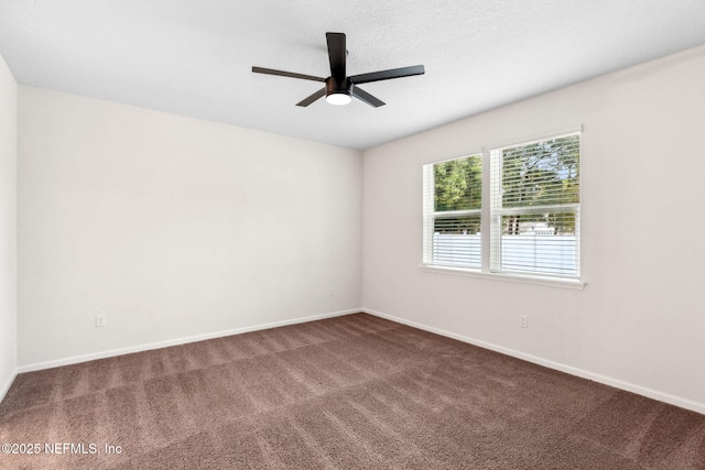 carpeted spare room with ceiling fan and baseboards