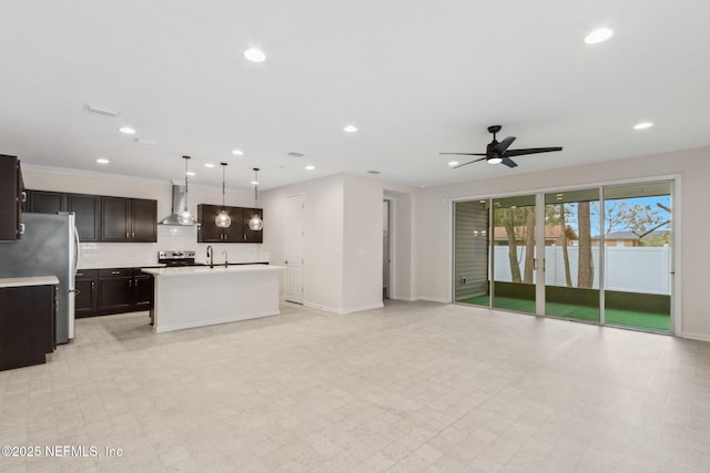 kitchen featuring wall chimney exhaust hood, appliances with stainless steel finishes, open floor plan, light countertops, and light floors