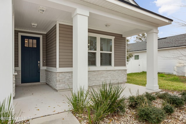 doorway to property with stone siding and a porch