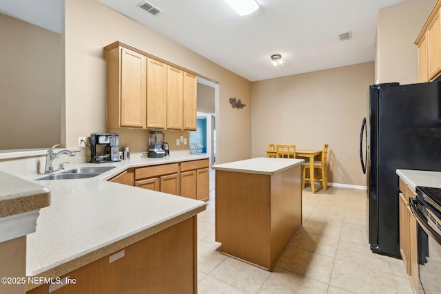 kitchen featuring light brown cabinets, a sink, visible vents, and a center island