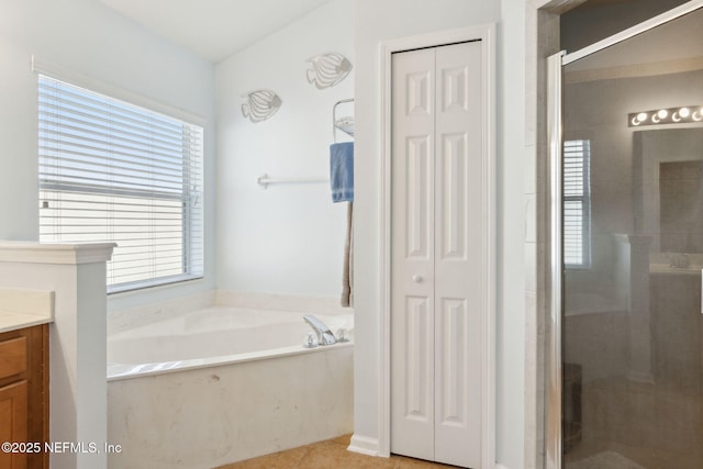 full bathroom with a stall shower, a closet, a garden tub, and vanity