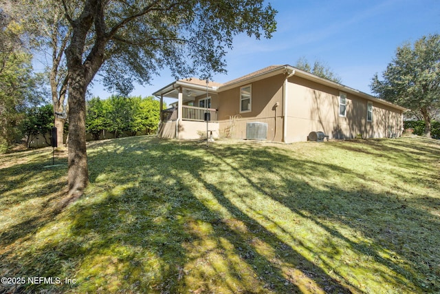 back of house with central air condition unit and a lawn