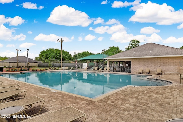 pool with a patio area and fence