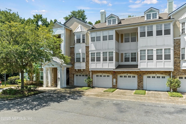 townhome / multi-family property featuring a garage, roof with shingles, driveway, and board and batten siding