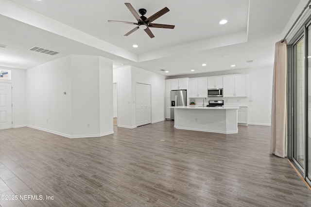 unfurnished living room featuring ceiling fan, recessed lighting, wood finished floors, visible vents, and baseboards