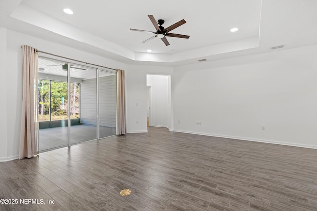 unfurnished bedroom with wood finished floors, visible vents, baseboards, access to exterior, and a tray ceiling