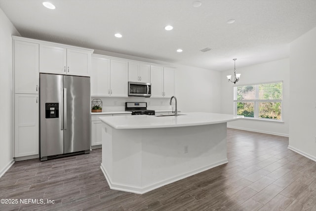 kitchen with stainless steel appliances, a sink, white cabinetry, dark wood-style floors, and an island with sink