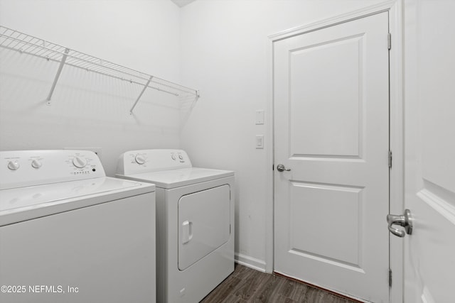 clothes washing area with laundry area, washing machine and dryer, baseboards, and dark wood finished floors