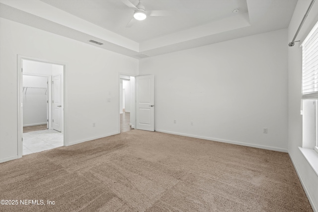 unfurnished bedroom featuring carpet floors, visible vents, baseboards, a raised ceiling, and ensuite bath