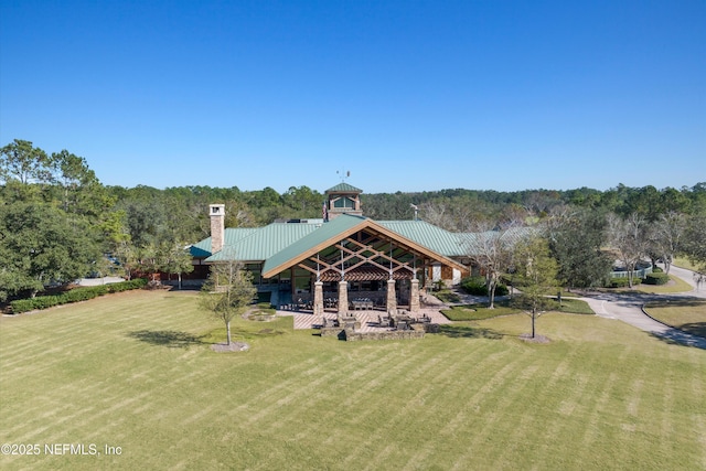 back of property featuring metal roof, a yard, and a chimney