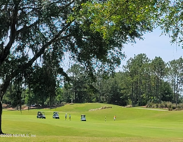 view of property's community featuring view of golf course and a lawn