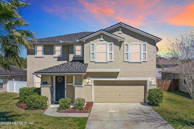 traditional home with stucco siding, concrete driveway, a front lawn, and fence