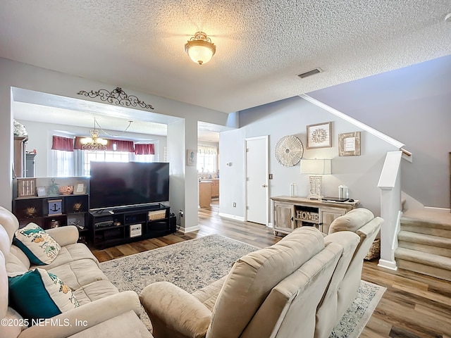 living room with visible vents, a chandelier, stairway, wood finished floors, and a textured ceiling