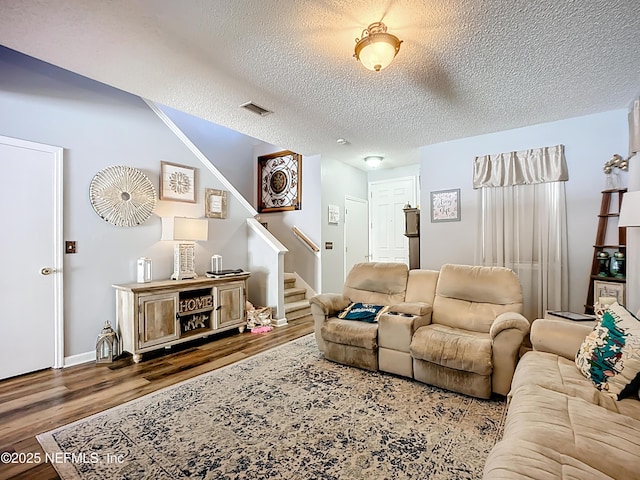 living area featuring stairway, a textured ceiling, visible vents, and wood finished floors