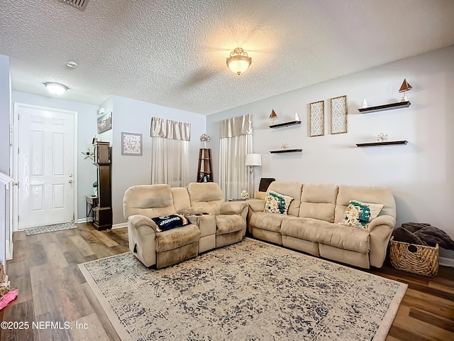 living room featuring a textured ceiling, baseboards, and wood finished floors