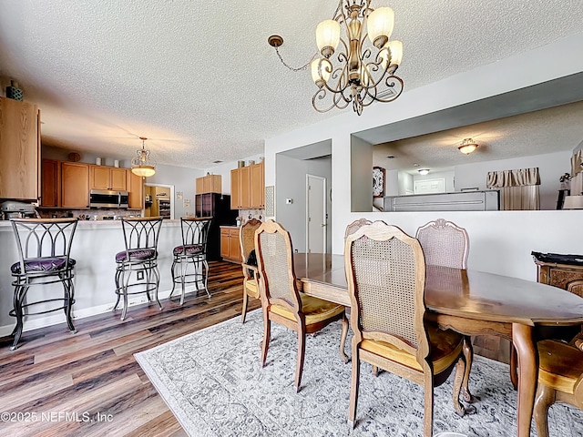 dining room with light wood-style floors, a chandelier, and a textured ceiling