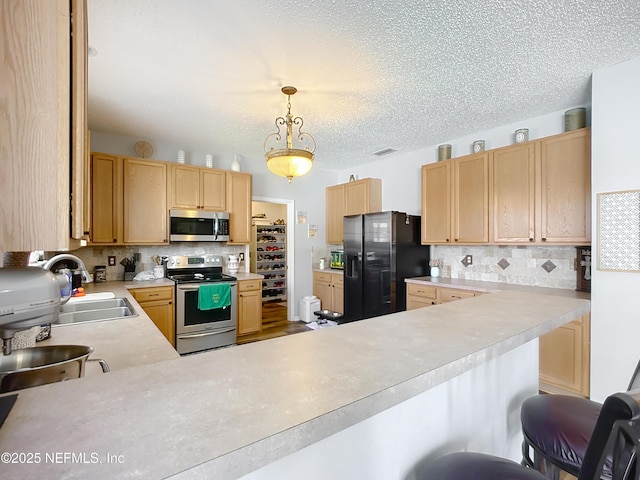 kitchen with decorative backsplash, appliances with stainless steel finishes, light countertops, and a sink