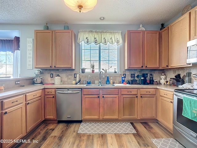 kitchen featuring light countertops, light wood-type flooring, appliances with stainless steel finishes, and a sink