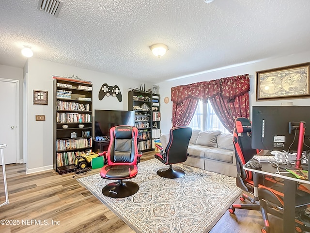 office area with visible vents, a textured ceiling, and wood finished floors