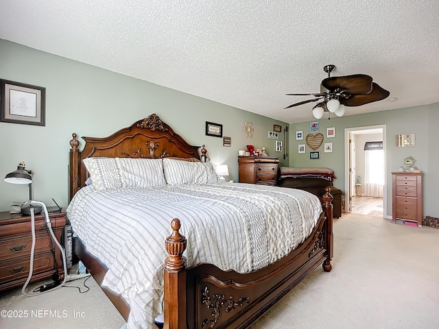 bedroom featuring light colored carpet, a textured ceiling, and a ceiling fan