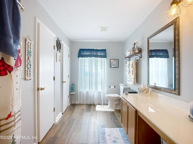 bathroom with toilet, wood finished floors, visible vents, and plenty of natural light