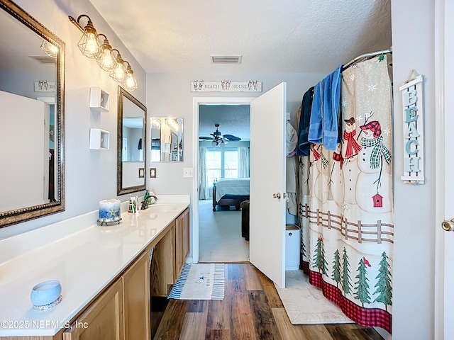 full bathroom featuring visible vents, vanity, ensuite bathroom, wood finished floors, and a textured ceiling