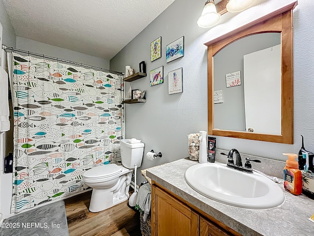 full bathroom featuring toilet, a textured ceiling, vanity, and wood finished floors