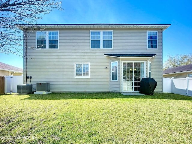 rear view of property featuring a fenced backyard, central air condition unit, and a yard