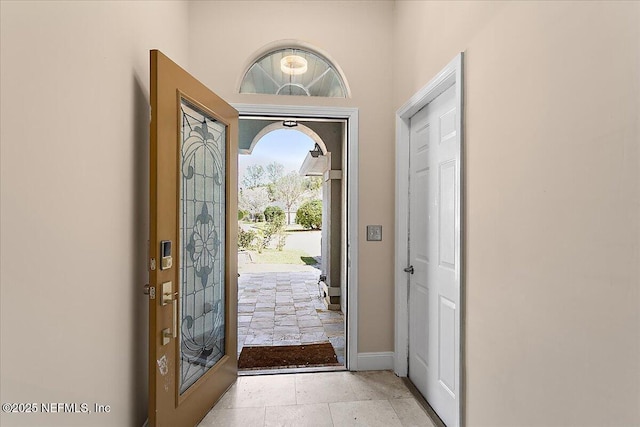 foyer entrance with baseboards and stone tile flooring