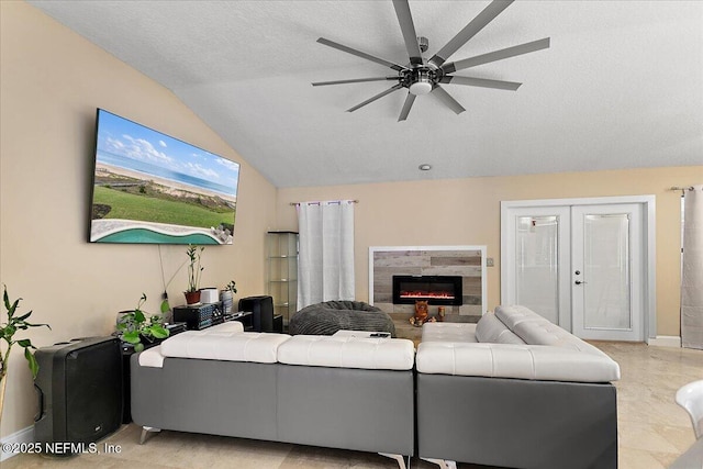 living room with ceiling fan, lofted ceiling, french doors, a glass covered fireplace, and a textured ceiling