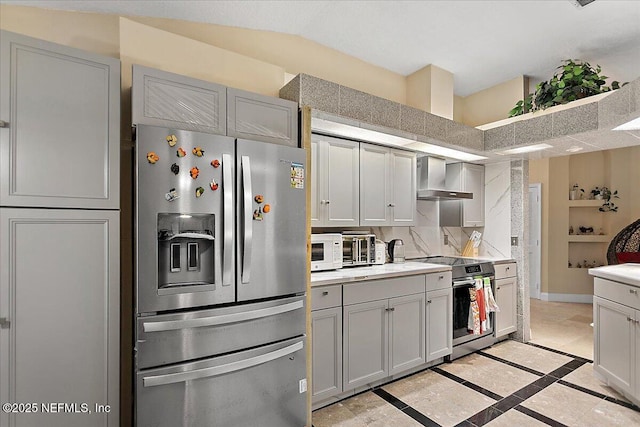 kitchen with decorative backsplash, appliances with stainless steel finishes, light countertops, and wall chimney range hood