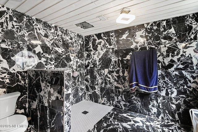 bathroom featuring tile walls, toilet, and tiled shower