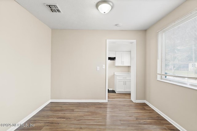 unfurnished room with visible vents, baseboards, and wood finished floors