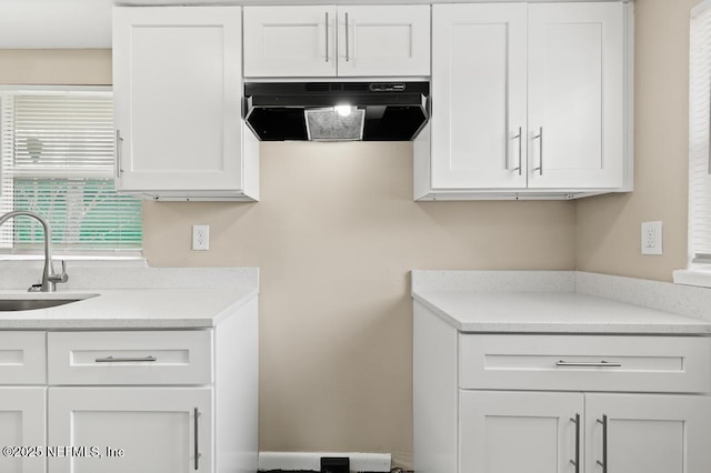 kitchen featuring a sink, white cabinetry, and under cabinet range hood