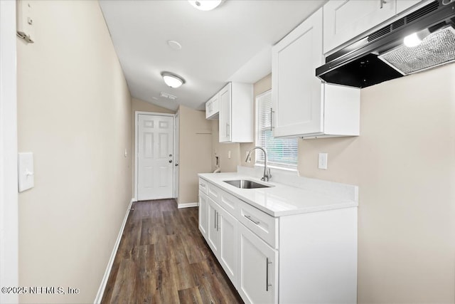 kitchen featuring light countertops, white cabinets, a sink, under cabinet range hood, and baseboards