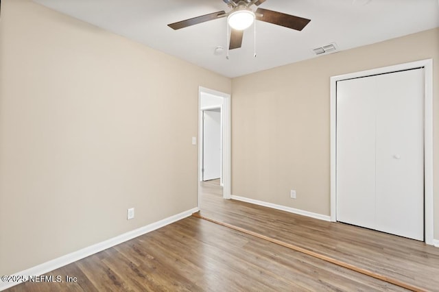 unfurnished bedroom with baseboards, visible vents, ceiling fan, wood finished floors, and a closet