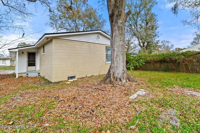 view of property exterior with entry steps, crawl space, fence, and a lawn