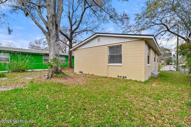 view of side of property with crawl space, a yard, and fence