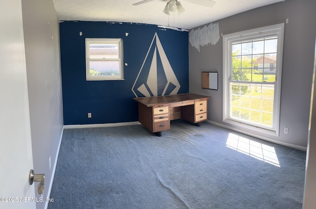 unfurnished office featuring a wealth of natural light, baseboards, a ceiling fan, and carpet flooring