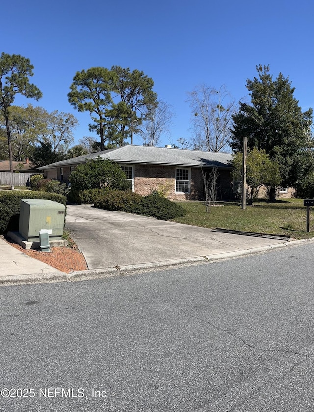 view of front of property with a front yard, concrete driveway, and brick siding