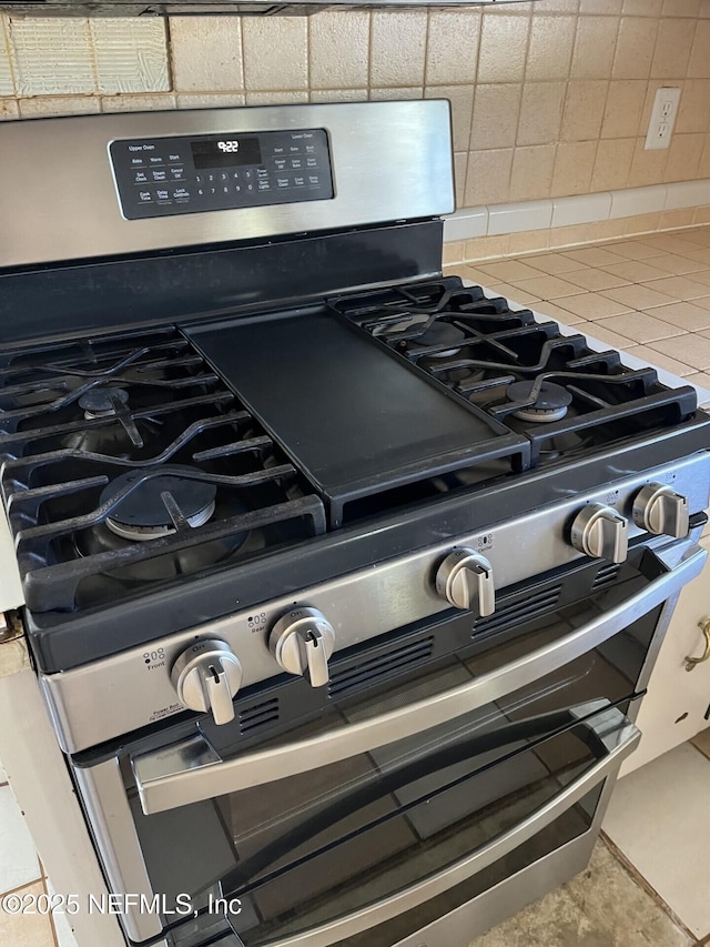 details featuring range with two ovens, light countertops, and decorative backsplash