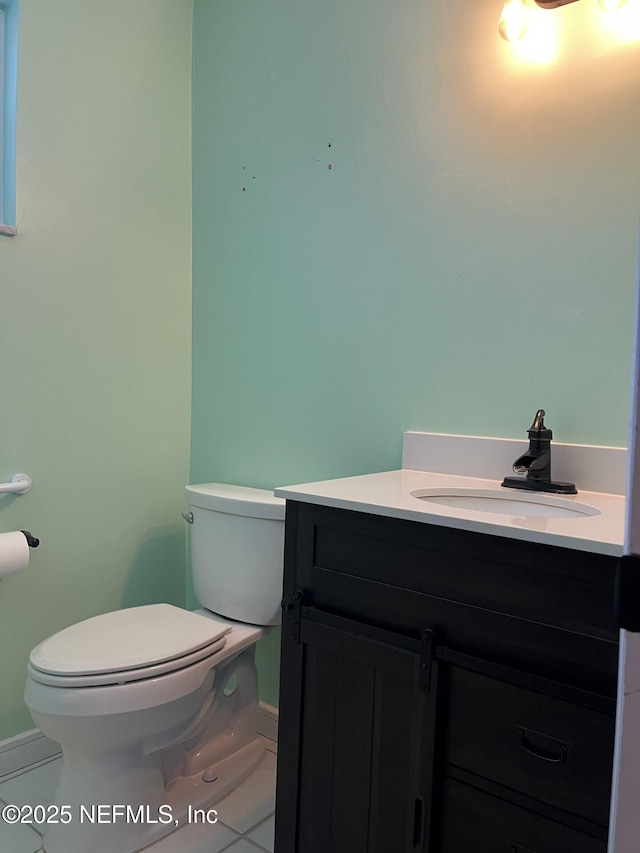 half bathroom featuring tile patterned flooring, vanity, and toilet