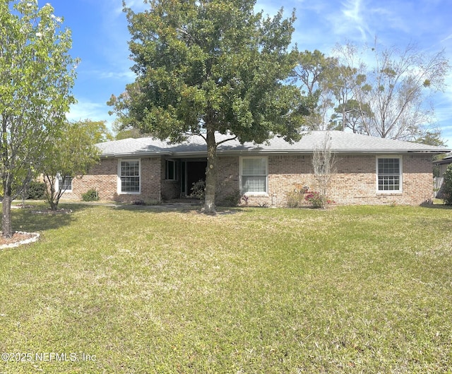 back of house with brick siding and a yard