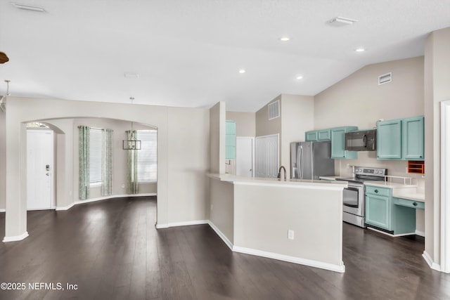 kitchen featuring light countertops, vaulted ceiling, a peninsula, stainless steel appliances, and dark wood-style flooring